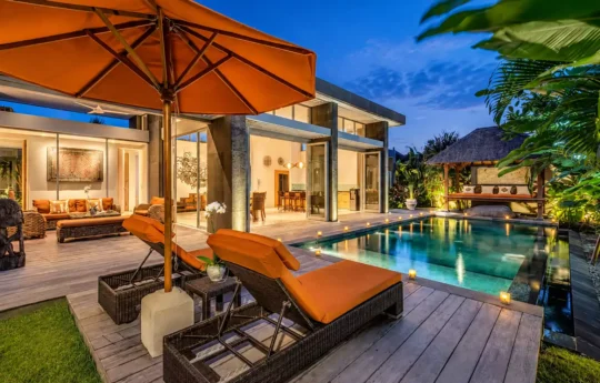 Nighttime views of Villa Indah Aramanis Estate exterior with pool and daybeds in foreground